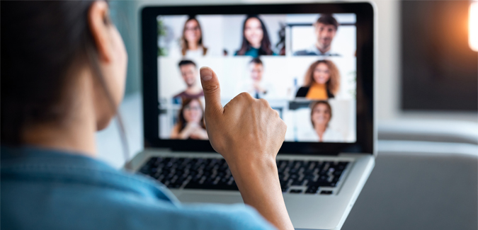 Person holding a thumbs up in front of a laptop video conference